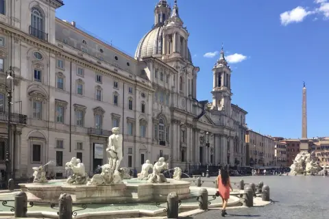 Una donna passeggia nella splendida Piazza Navona, ammirando la Fontana dei Quattro Fiumi e la maestosa chiesa.