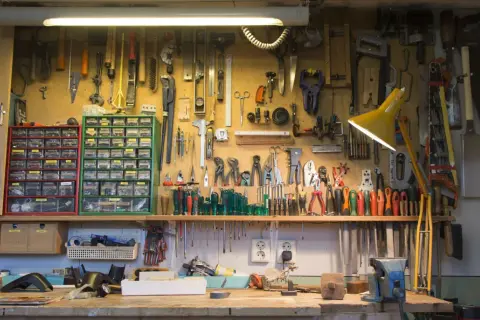 Un agencement d'atelier bricolage bien organisé, avec des outils suspendus et des tiroirs de rangement remplis.