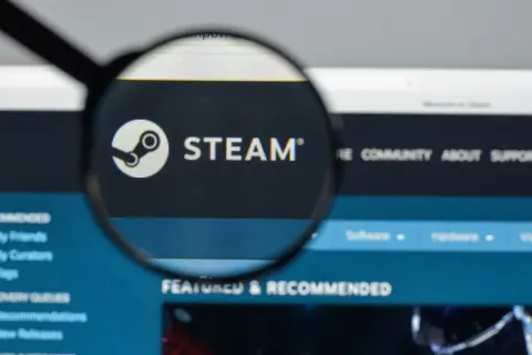 Lupa powiększa logo Steam na ekranie komputera.