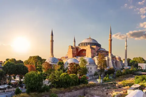 Majestatyczny meczet Hagia Sophia w Stambule, z minaretami i kopułami, oświetlony zachodzącym słońcem.