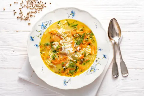 Aromaticzna zupa koperkowa z ryżem, marchewką i zielonym koperkiem, podana w ozdobnym talerzu.