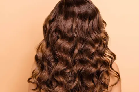 Cabello castaño largo y ondulado, con ondas definidas. Descubre cómo peinar pelo ondulado para lograr este look.