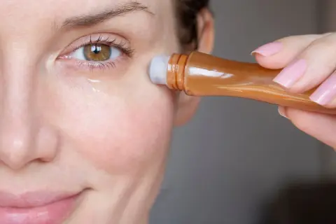 Kobieta aplikuje serum pod oczy, by zredukować widoczne zmarszczki pod oczami.