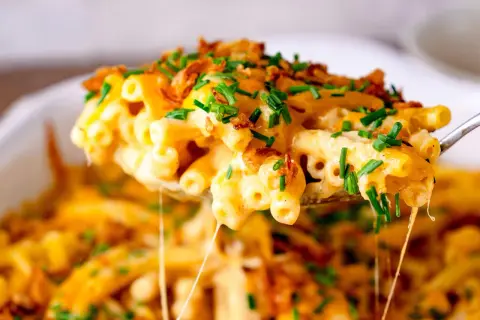 Cremiges Mac and Cheese mit knusprigen Zwiebeln und frischem Schnittlauch, das Käse zieht. Ein Genuss!
