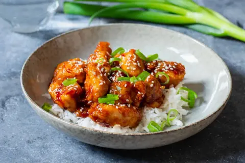 Krispiga kycklingbitar i en söt och syrlig sås, toppade med sesamfrön och salladslök. Ett perfekt recept med kyckling för en snabb middag.