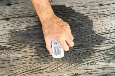 Hand håller en bit trä för att rengöra trallrent eller såpa.