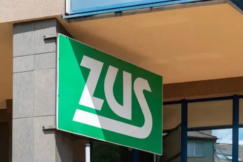 Zielony szyld ZUS z białym logo. Mały ZUS plus, symbol bezpieczeństwa i wsparcia.