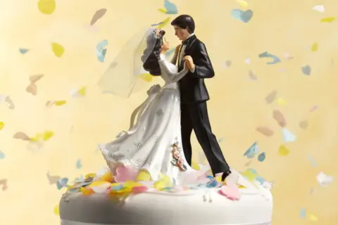 Statua di sposi su torta nuziale, con coriandoli colorati che volano. 75 anni di matrimonio, che nozze sono!