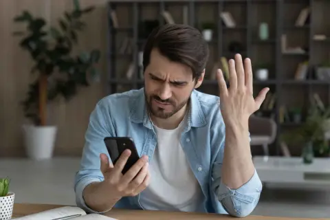 Mężczyzna zmartwiony przegrzewaniem się telefonu. Dba o bezpieczną temperaturę urządzenia, by uniknąć uszkodzeń.