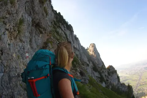 Wanderin auf dem Salzburger Hochthron, mit Blick auf steile Felsen und das Tal.
