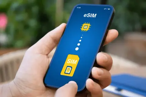 Dłoń trzyma smartfon z ekranem pokazującym ikonę karty SIM i symbol chipa, symbolizujące kartę eSIM.