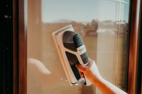Ręka trzymająca odkurzacz do okien Karcher, pokazująca, jak myć okna.