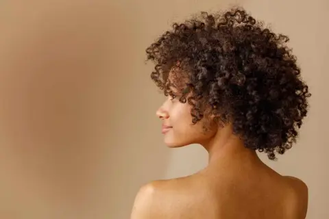 Perfil de una mujer con un espectacular pelo afro, rizos definidos y un rostro sereno.