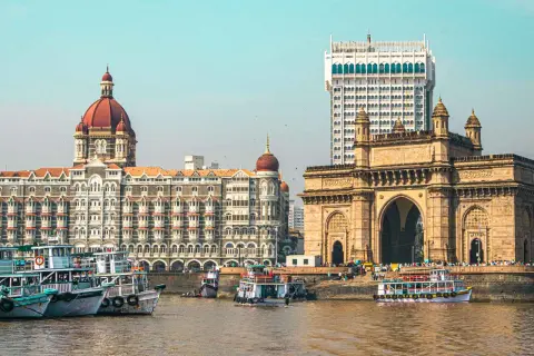 Brama Indii i hotel Taj Mahal Palace w Mumbaju, Indie. Wokół pływają łodzie.