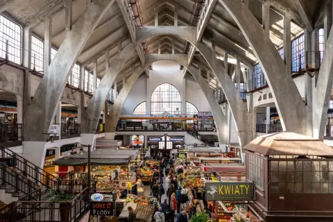 Das Innere der Markthalle, ein Wahrzeichen von Wrocław, mit seinen beeindruckenden Betonbögen und dem lebhaften Treiben der Marktstände.