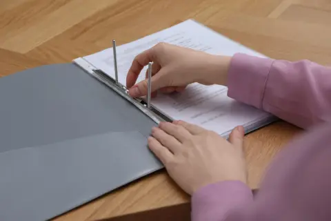 Mani che archiviano documenti in una cartellina, un promemoria su per quanti anni bisogna conservare le bollette.
