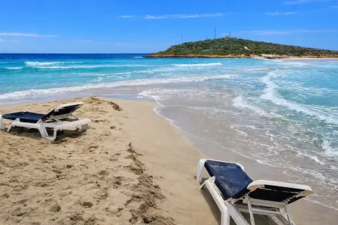 Plaża na Cyprze w styczniu. Dwa puste leżaki czekają na plaży, a turkusowe morze delikatnie faluje.
