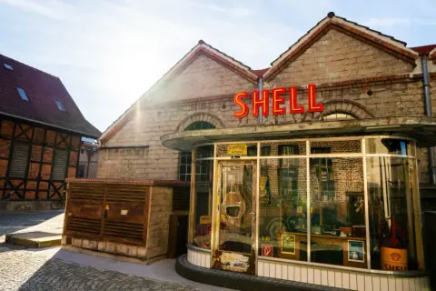 Retro Shell-Tankstelle im Motorworld Metzingen, mit Fachwerkhaus im Hintergrund.