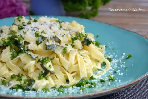 Assiette de tagliatelles de courgettes crémeuses, parsemées de persil frais et de parmesan râpé. Un délice léger et savoureux.