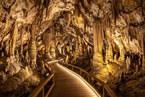 Drewniana ścieżka prowadzi przez jaskinię pełną stalaktytów i stalagmitów. To piękny przykład tego, czym jest speleologia.
