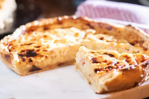 Ein köstliches Quiche Rezept, goldbraun gebacken, mit einem Stück zum Probieren.