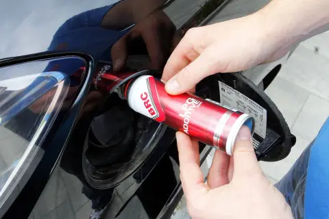 Ręce wlewają dodatek do LPG z puszki BRC do baku samochodu, dbając o czyszczenie wtrysków lpg.