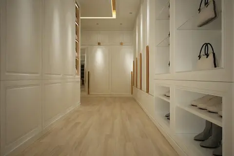 Elegancki, długi korytarz z zabudową garderobianą. Aranżacje wnętrza z białymi frontami, złotymi uchwytami, półkami na buty i torebki.