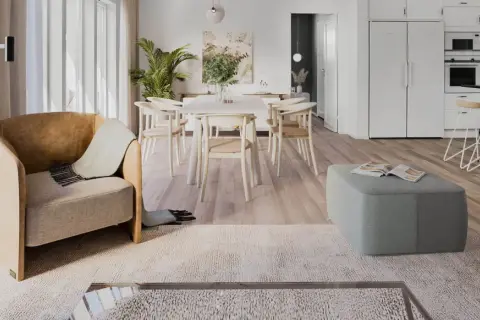 Ett ljust och luftigt vardagsrum med matplats i klassisk nordisk design. En bekväm fåtölj och en grön pall skapar en inbjudande atmosfär.