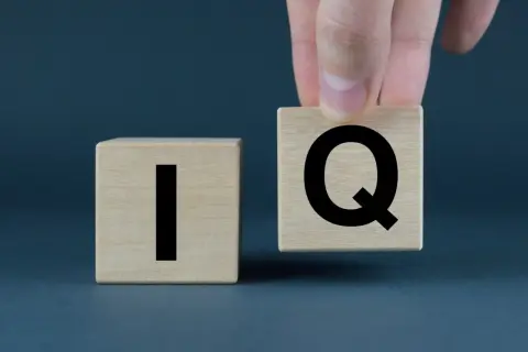 Dłoń układa kostkę z literą "Q" obok kostki z literą "I". Co to jest IQ?