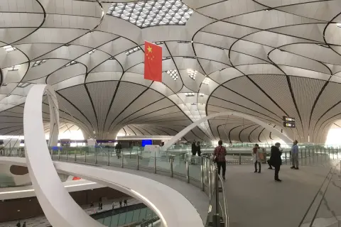 Nowoczesne lotniska w Chinach zachwycają architekturą. Wnętrze terminalu z flagą Chin i futurystycznym dachem.