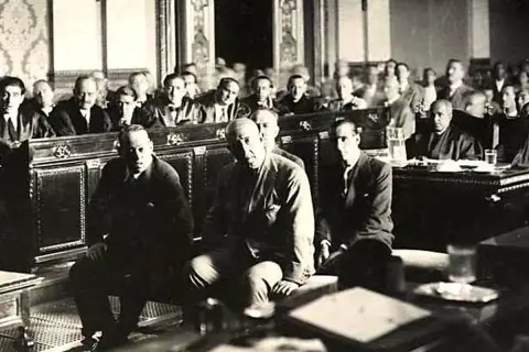 Hombres sentados en una sala, uno de ellos es José Sanjurjo y Prieto, en un evento histórico.