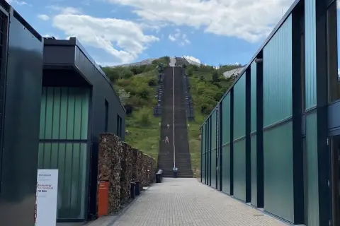 Der **Metabolon** in Lindlar, ein Ort für Forschung und Lehre der TH Köln, mit einer langen Treppe, die zu einem Hügel führt.