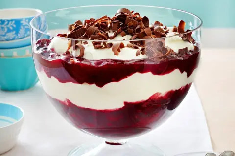 Schichtdessert mit Kirschen und einer luftigen Creme aus Mascarpone, garniert mit Schokoladenlocken.