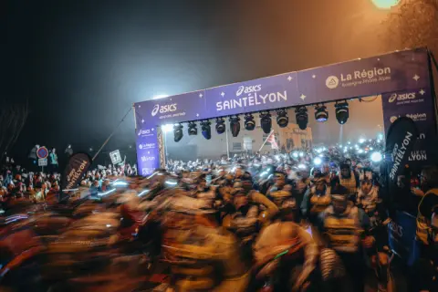 Foule de coureurs au départ de la SaintéLyon, sous un portique illuminé. Les résultats de cette course nocturne promettent d'être intenses.