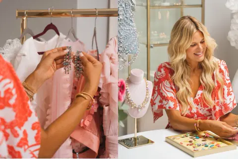 Caroline Svedberg Smycken: En kvinna väljer glittrande örhängen bland rosa kläder. En annan kvinna sorterar stenar för smycken.
