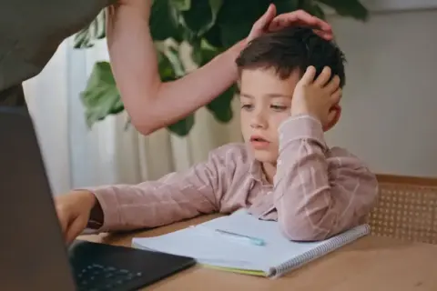 Chłopiec z rezygnacją opiera głowę na dłoni, wyraźnie widać, że dziecko nie chce się uczyć.