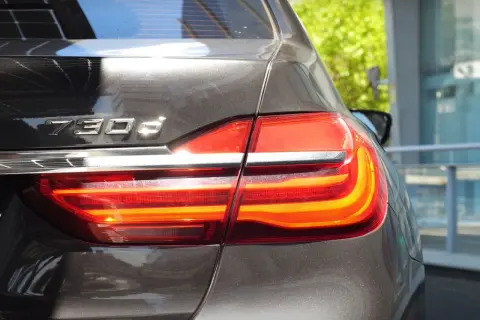 Tylna część lśniącego BMW 730d z włączonymi światłami stopu.