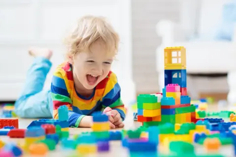 Radosny chłopiec bawi się klockami. Czy opiekun w żłobku zarabia tyle, by zapewnić dzieciom takie radosne chwile?