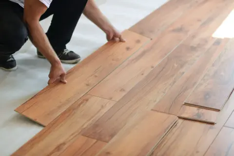 Hands installing laminate flooring. Is laminate flooring hard to install? This DIY project looks manageable.