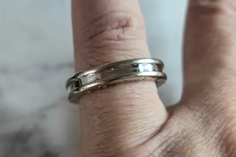 Anillo Bulgari de oro blanco y detalles pulidos, adornando un dedo con su diseño elegante y atemporal.