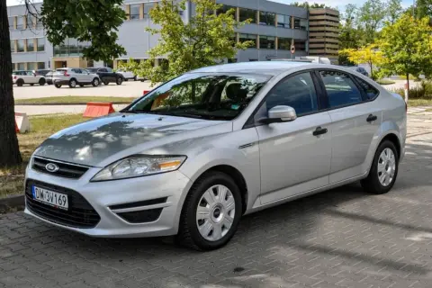 Srebrny Ford Mondeo MK4 2.0 TDCI zaparkowany na kostce brukowej przed budynkiem.