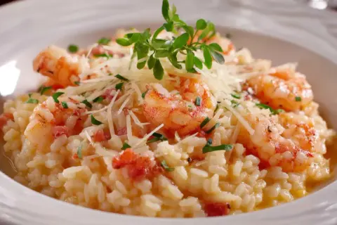 Un crémeux risotto crevettes, garni de parmesan râpé et de persil frais, avec quelques touches de bacon croustillant.