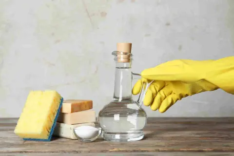 Ingredienti per un detersivo lavatrice fatto in casa da Benedetta: aceto bianco in una caraffa, sapone, bicarbonato e una spugna.