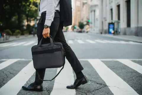 Biznesmen w garniturze idzie przez pasy, niosąc teczkę. Może właśnie wraca z pracy, myśląc o swojej **dieta krajowa**.