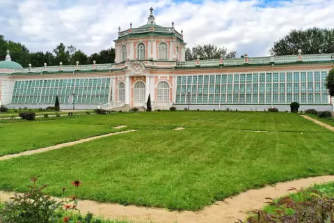 Przepiękny, różowo-zielony pałac z przeszklonymi ścianami, przypominający **ogród zimowy w domu**, otoczony jest zadbanym trawnikiem i alejkami.