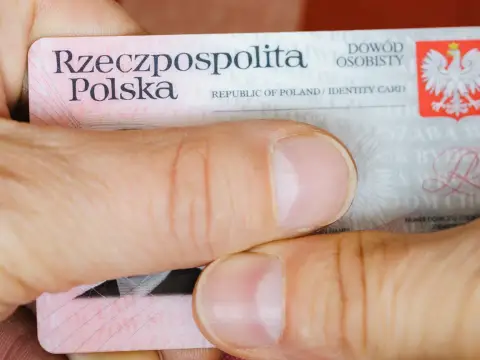 Dłonie trzymają polski dowód osobisty. Widoczny jest numer dowodu osobistego.