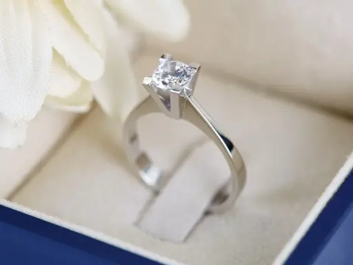 Anello con diamante solitario in un cofanetto blu, un simbolo di amore eterno. Il diamante gioielleria brilla.
