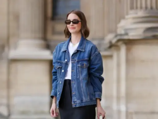 Donna con occhiali da sole indossa un outfit giacca jeans donna, t-shirt bianca e gonna nera.