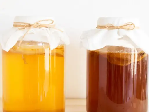 Dwa słoje z kombuchą, jeden jasnożółty, drugi ciemnobrązowy. Czy kombucha jest zdrowa? To pytanie nurtuje wielu miłośników napojów fermentowanych.