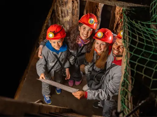 Rodzina w kaskach zwiedza kopalnię soli w Wieliczce. Dzieci z mapą w ręku, gotowe na przygodę!
